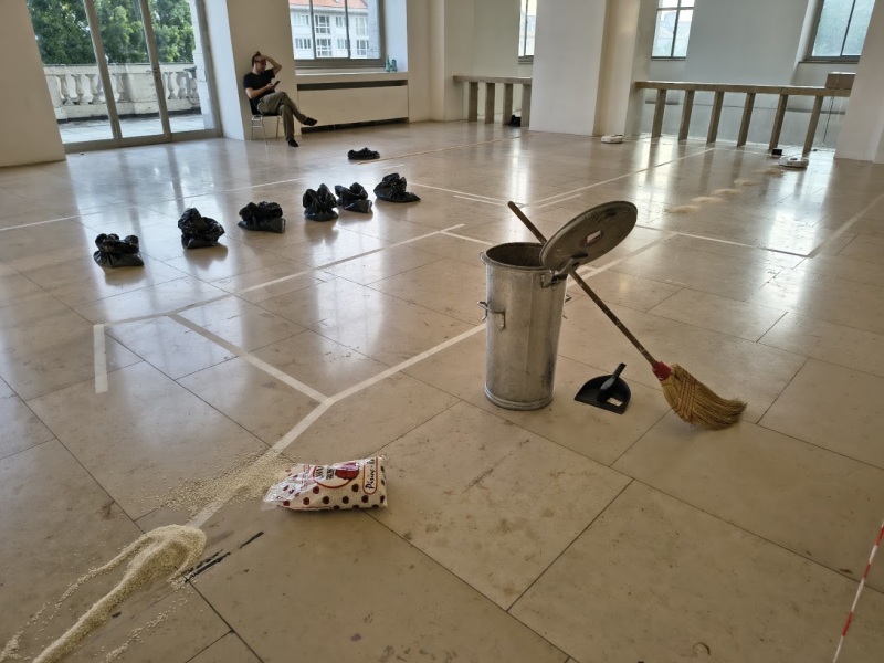 Installation zur Care-Arbeit mit Saugrobotern, Mülltonne, Besen und verstreutem Reis